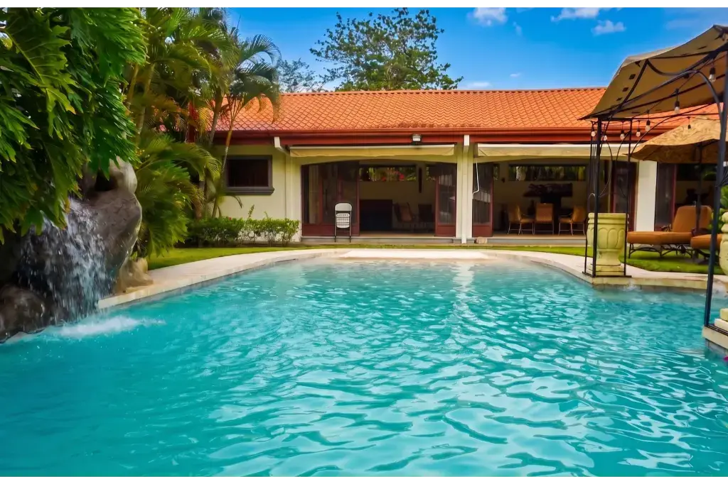 Turquoise pool and waterfall feature beside a covered terrace at Las Melinas Sanctuary, Santa Ana